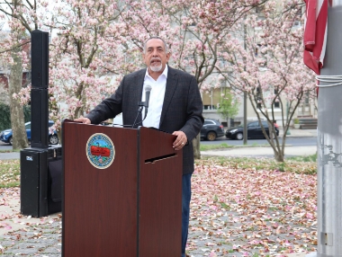 Reading’s mayor behind a podium with cherry blossom trees in the background